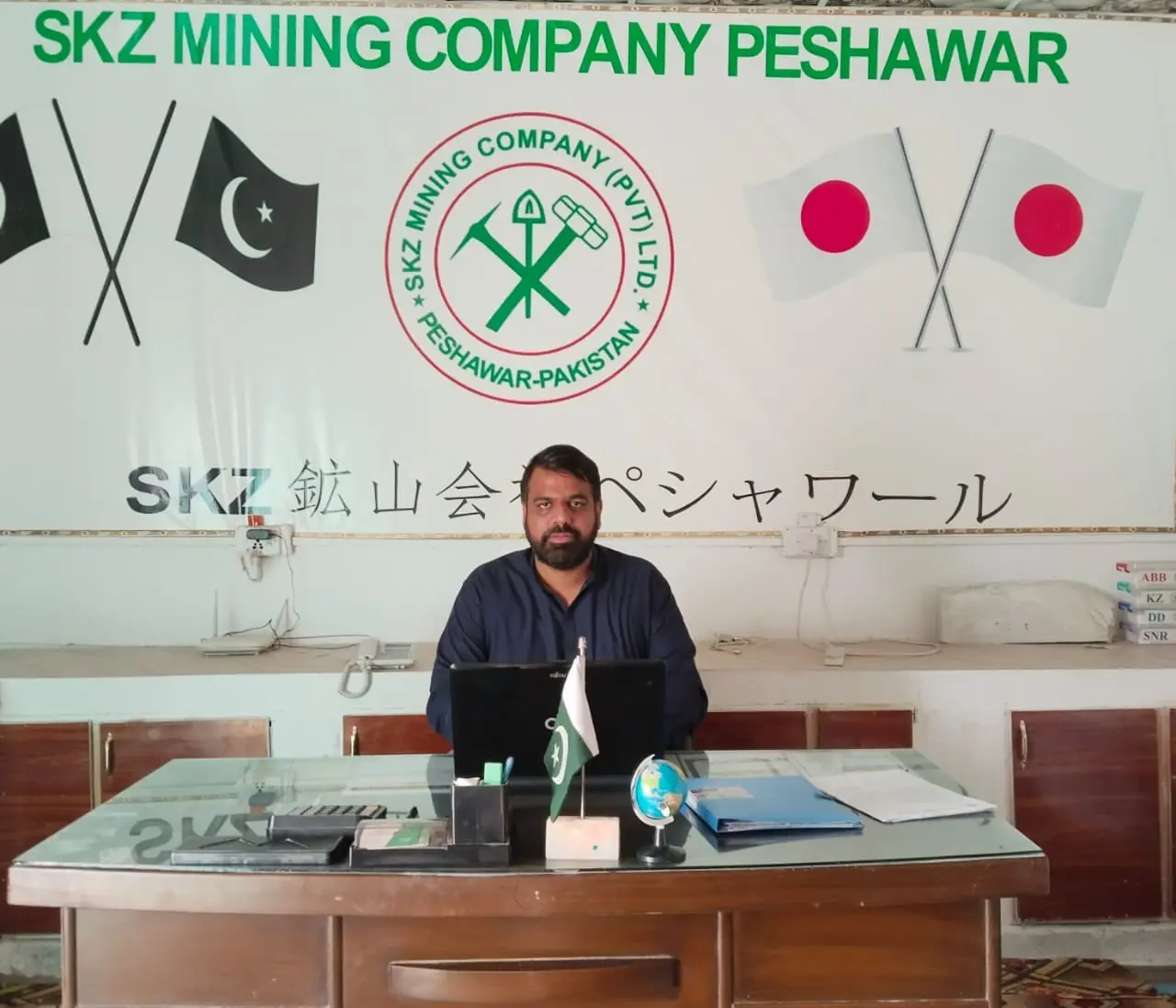 An office desk in front of a signboard reading SKZ Mining Company Peshawar