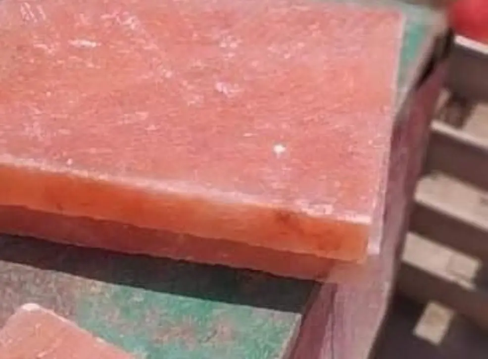 A rectangular pink salt slab resting on a green surface